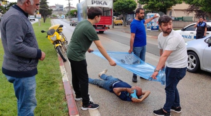Bursa'da kaza yapan motorcuyu yağmurdan çöp poşetiyle korudular