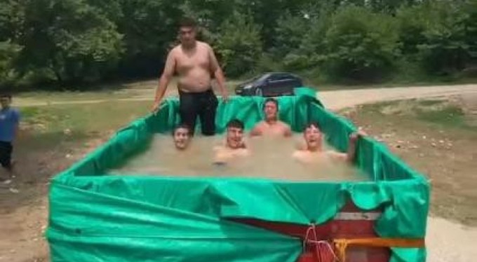 Bursa'da traktör römorkuna doldurdukları suyla serinlediler